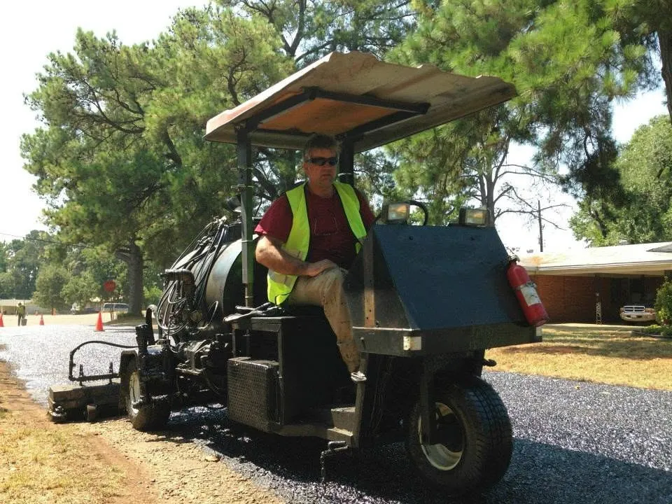 TriTechnologies founder Jeff Pokorny running the rejuvenator spray unit along a freshly treated tree-lined roadway.