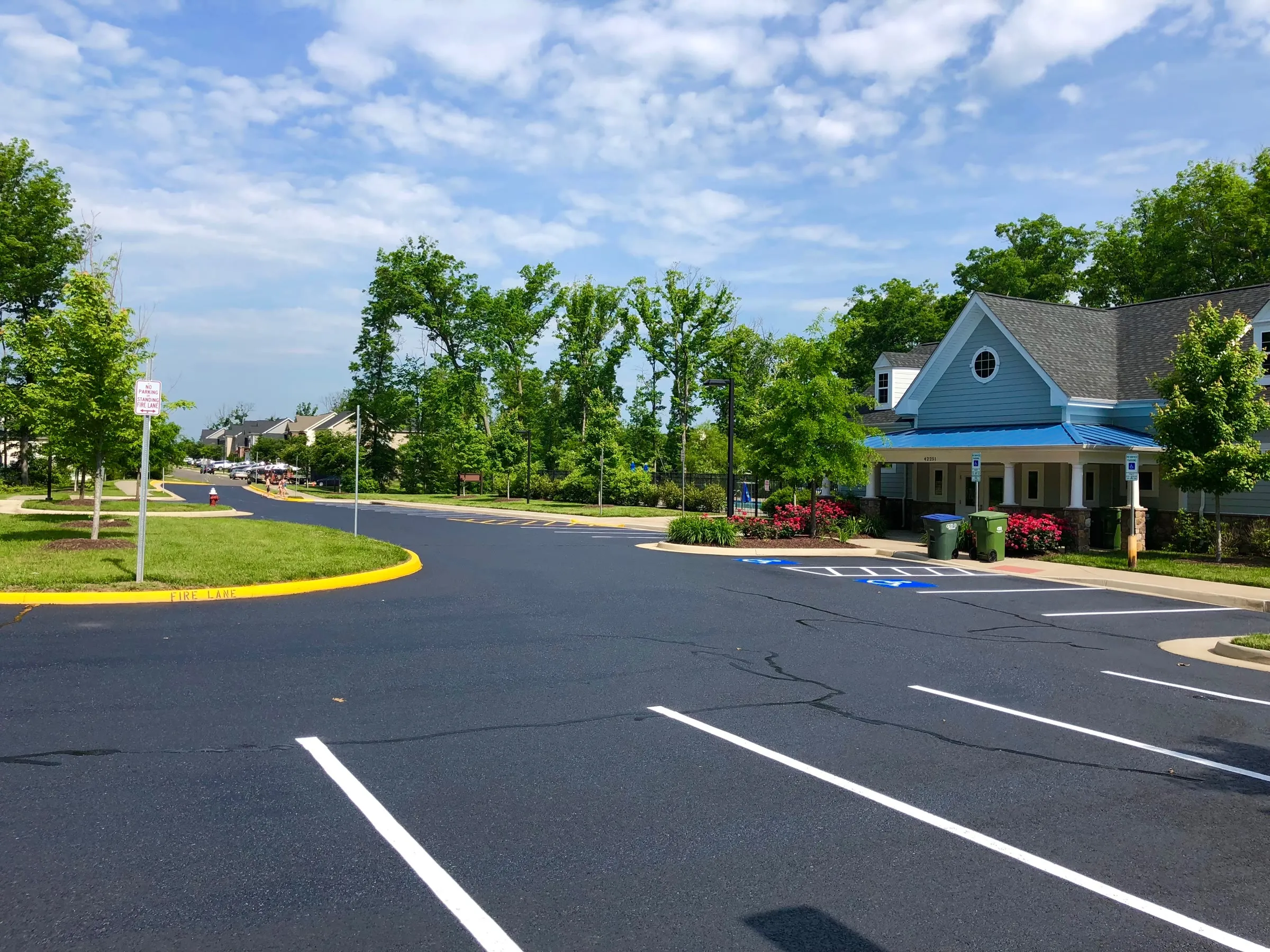 Freshly paved and striped HOA community street beside a neighborhood clubhouse.